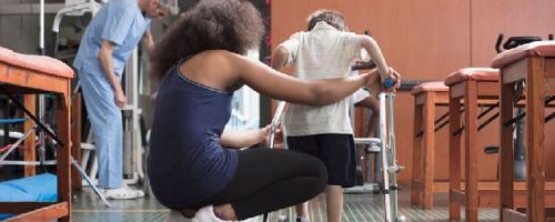 femme qui aide un enfant en situation dhandicap à se déplacer avec un support de maintient: Journée Mondiale du handicap : l’équipe de la Clinique Saint Charles Elsan