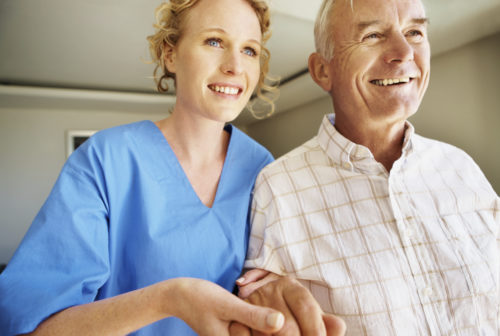 photo mettant en avant une soignante en blouse bleu et un patient senior 