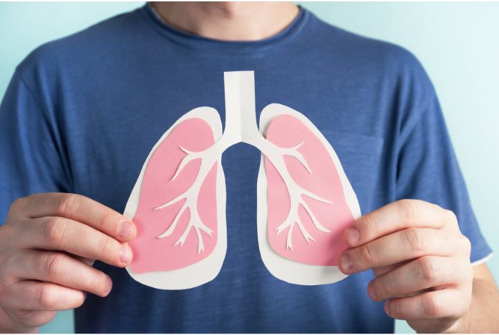 Double pneumonie ou pneumopathie bilatérale : un homme porte à la hauteur de son thorax, un schéma montrant deux poumons.