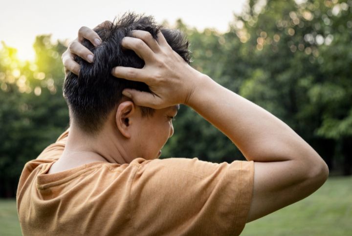 Hemorragie meningee : image d'un jeune homme brun se tenant la tete dans les mains. il souffre de cephalees