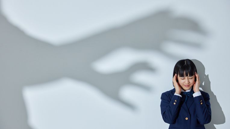 Lorazépam (Temesta) : effets, dosage, précautions et alternatives. Une jeune femme dans un coin se bouche les oreilles alors que l'ombre de grandes mains semble l'agresser.