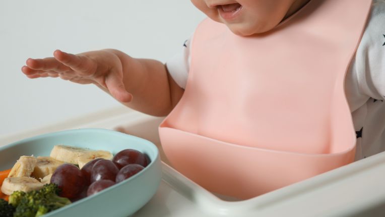 illustration de bébé devant un assiette de fruit 