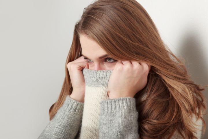 Phobie d'impulsion : image d'une femme rousse qui  cache son visage à l'aide de son pull