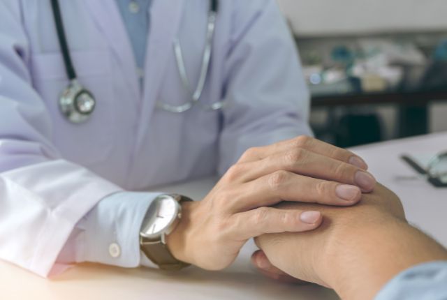 Adénocarcinome : un soignant tient la main d'un patient.