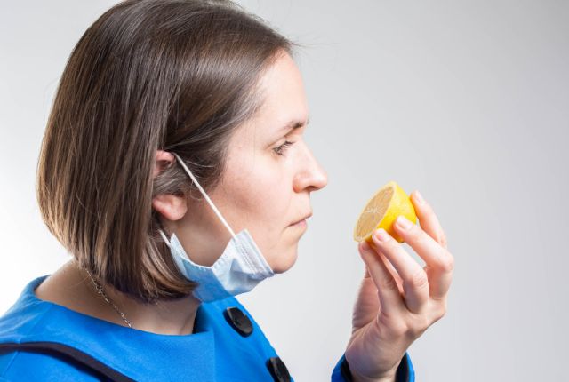 Anosmie : le trouble de l'odorat, ses causes et conséquences. Journée mondiale du 27 février 2025. Une femme ayant ôté son masque tente de sentir une moitié de citron.