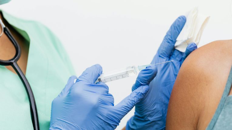 Vaccin contre le chikungunya à Marseille Bouchard. Image : gros plan sur une soignante avec des gants bleus s'apprêtant à vacciner une personne au niveau de l'épaule.