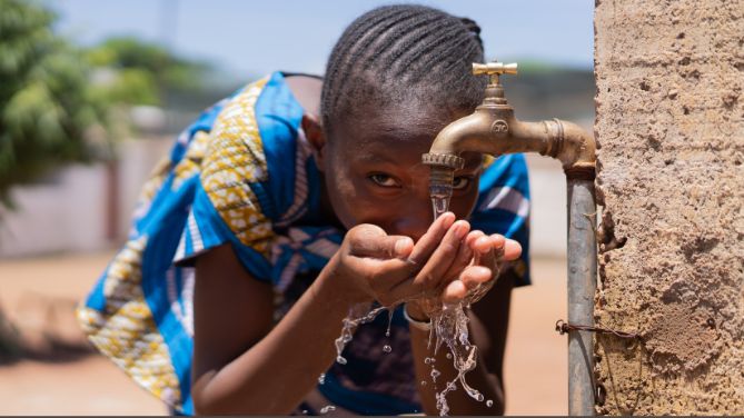 Cholera : inquiétante découverte sur une nouvelle souche. Image d'une enfant buvant de l'eau d'un robinet installé sur la voie publique, probablement en Afrique.