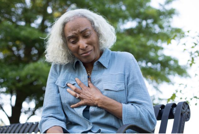 Douleur thoracique : une femme porte la main à la poitrine et semble souffrir.