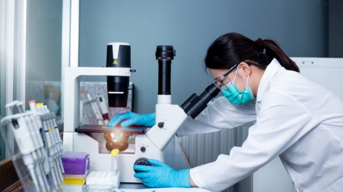 Examen anatomopathologique, de quoi parle-t-on ? Chercheuse penchée sur un microscope de laboratoire.