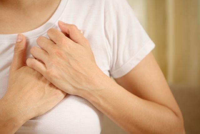Arythmie cardiaque : définition, causes, traitement. Image d'une femme qui porte ses deux mains à son cœur.