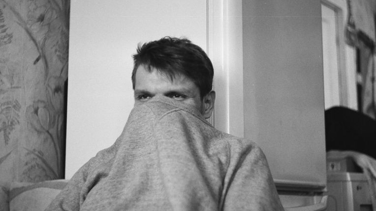 Grippe B ou grippe A : quelle différence ? Symptômes, durée, traitement. Un jeune-homme remonte le col de son sweat-shirt sur son nez.