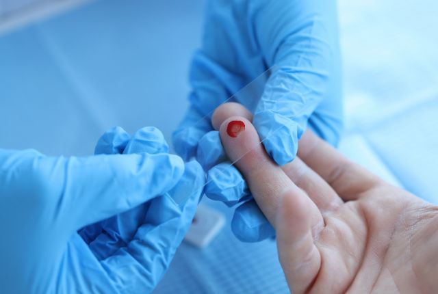 Hémoglobine, taux, basse, glyquée, élevée. Image d'un prélèvement d'une goutte de sang sur le bout du doigt avec une petite plaquette transparente.