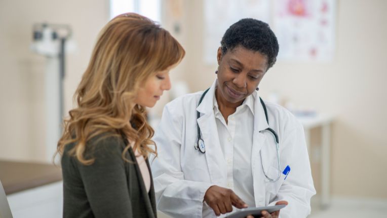 Santé des femmes : une soignante montre un document à une patiente dans une salle de soins.