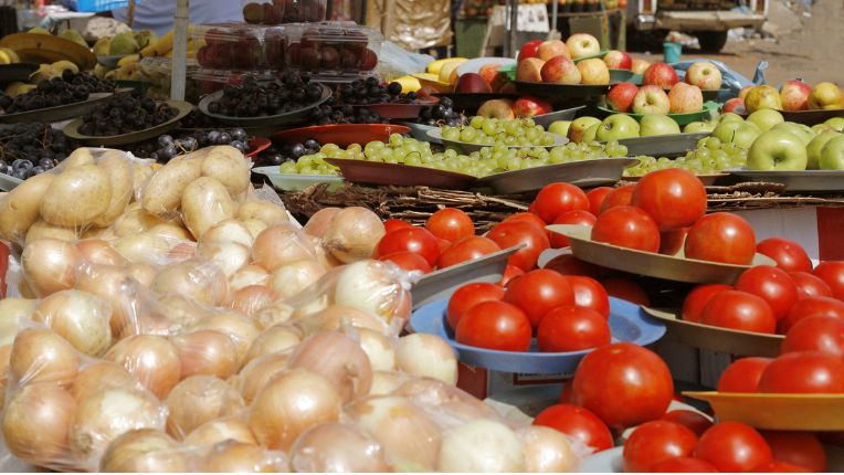 Etal de marché avec oignons, tomates, fruits : les touristes ont intérêt à peler les fruits, manger des aliments cuits et boire de l'eau en bouteille pour éviter la tourista.