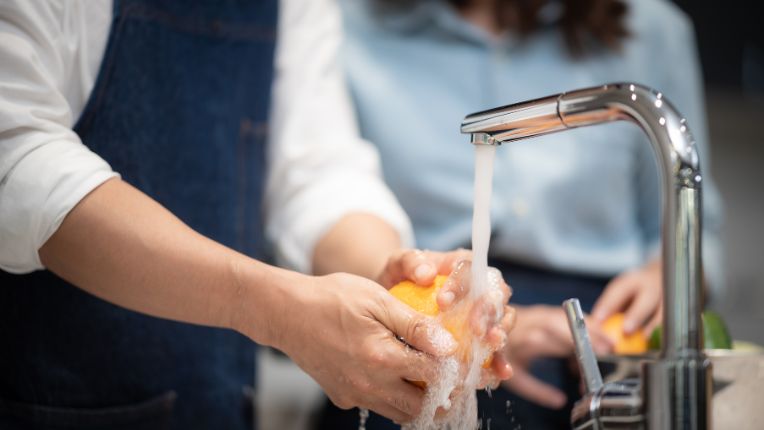 Vaccin hépatite A Toulouse.CVI Elsan. Visuel d'une personne dont on voit seulement les mains en train de nettoyer soigneusement un légume sous l'eau du robinet.