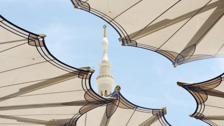 Quel vaccin contre la méningite pour l'Omra en Arabie saoudite ? Image d'un minaret à Médines surgissant au-dessus d'un immense parasol blanc.