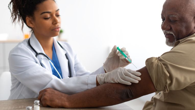 Vaccin tétanos Lyon. Une soignante vaccine un homme d'âge mûr dans le bras gauche.