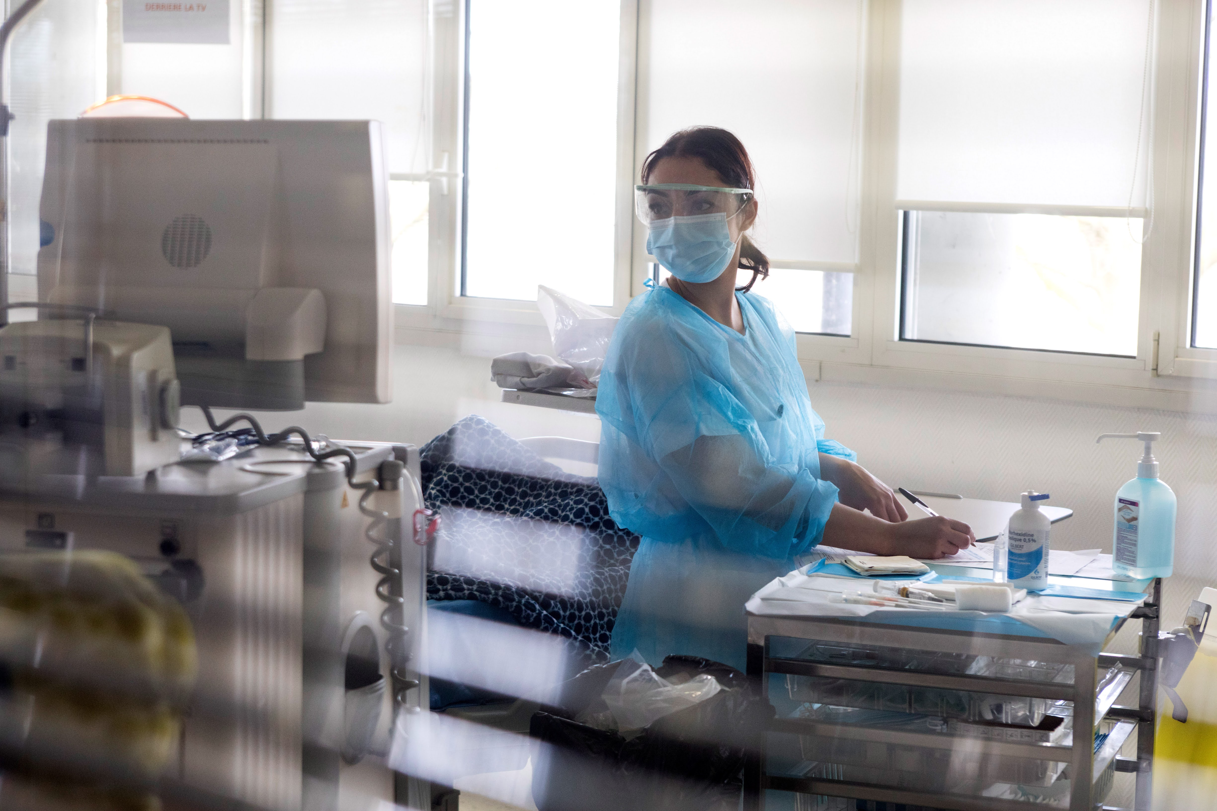 A doctor wearing a mask and lab coat reviewing information on a computer screen.”