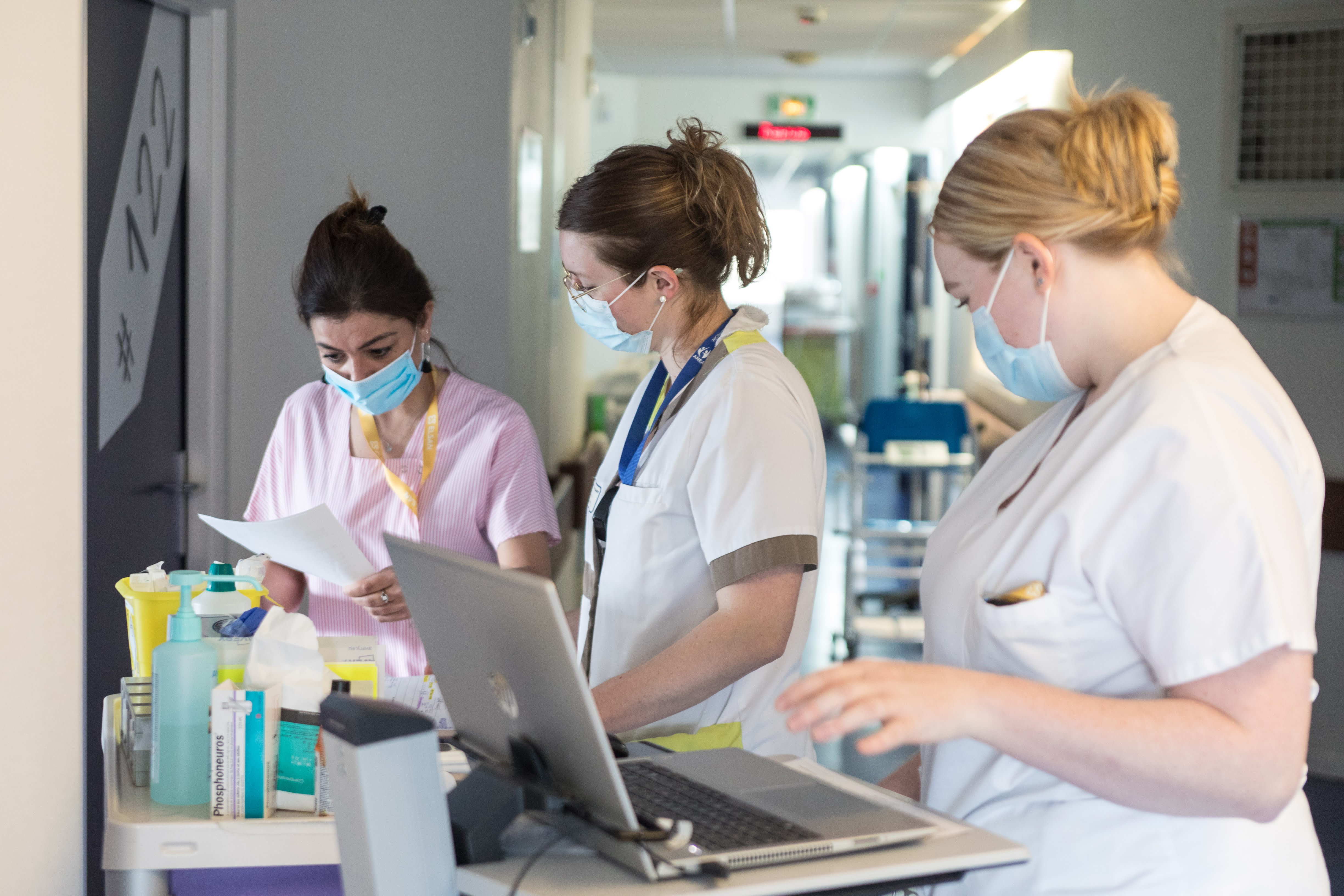 Three nurses focused and reviewing a patient’s file together.