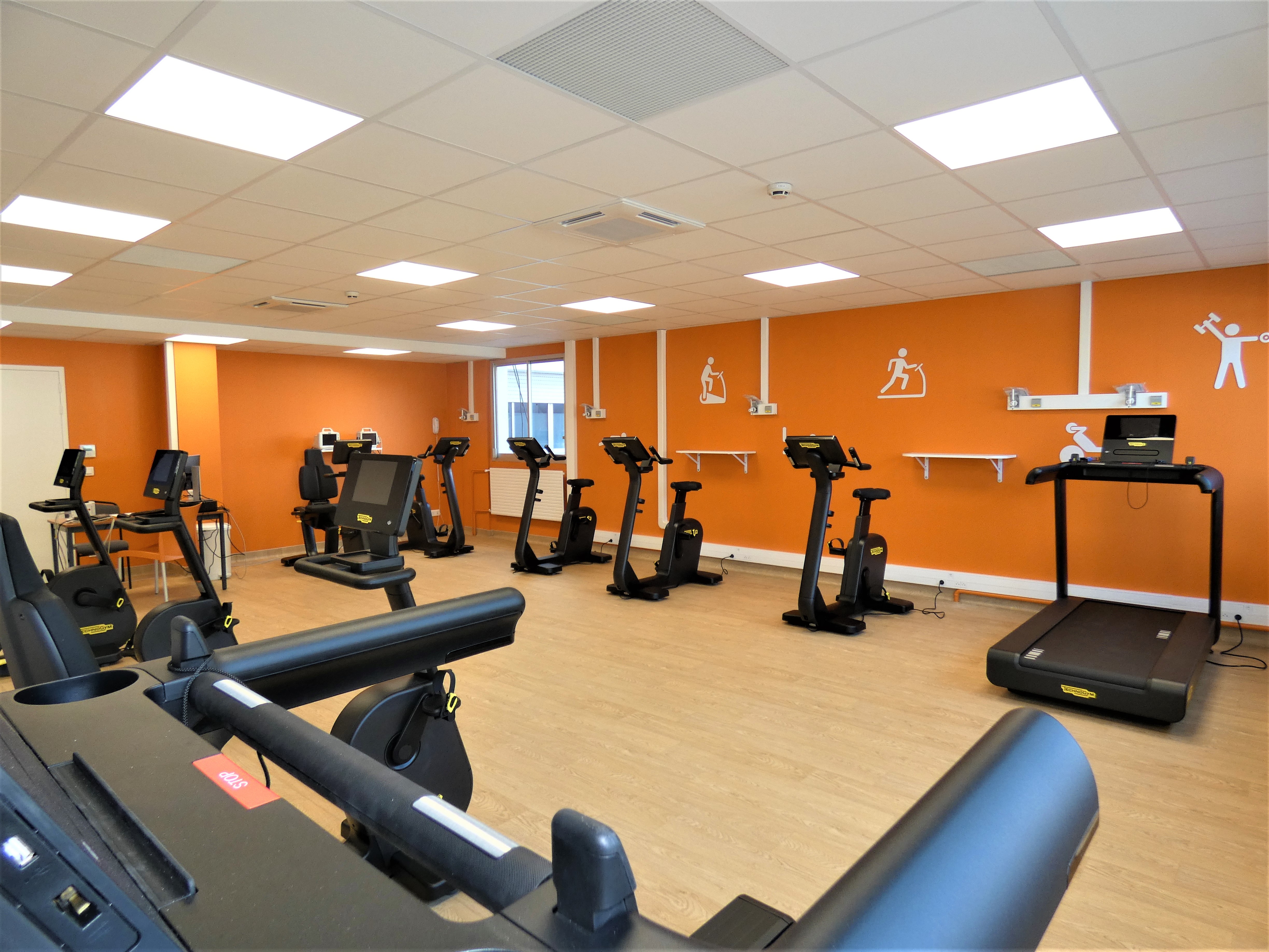 Salle de gym avec tapis de course, vélo pour réeducation