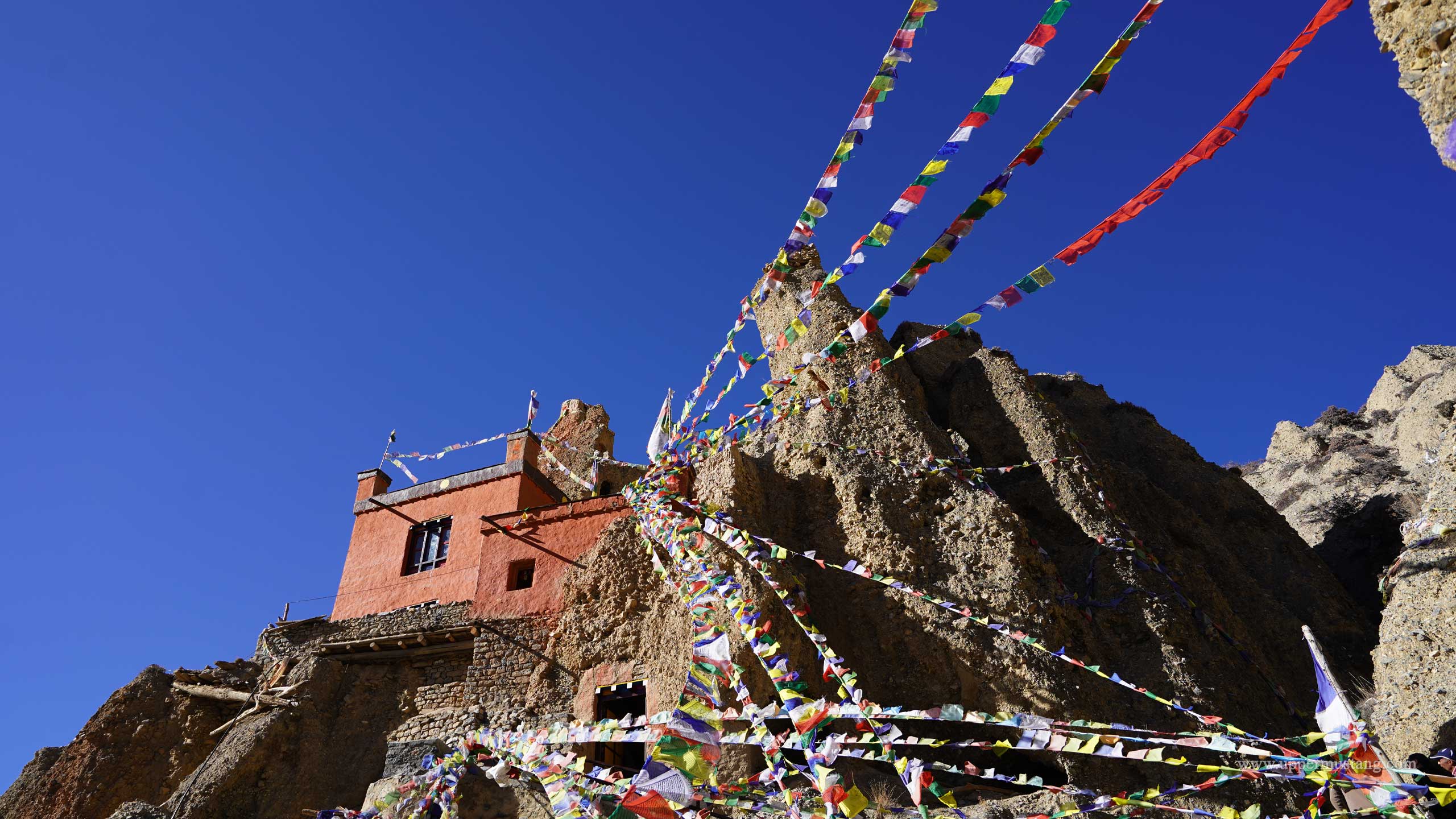 Sacred Chorten and Buddhist Statues Inside Luri Gompa Cave, Upper Mustang Nepal Colorful Tibetan Buddhist prayer flags at the entrance of Luri Gompa cave monastery near Ghara village, Upper Mustang Nepal