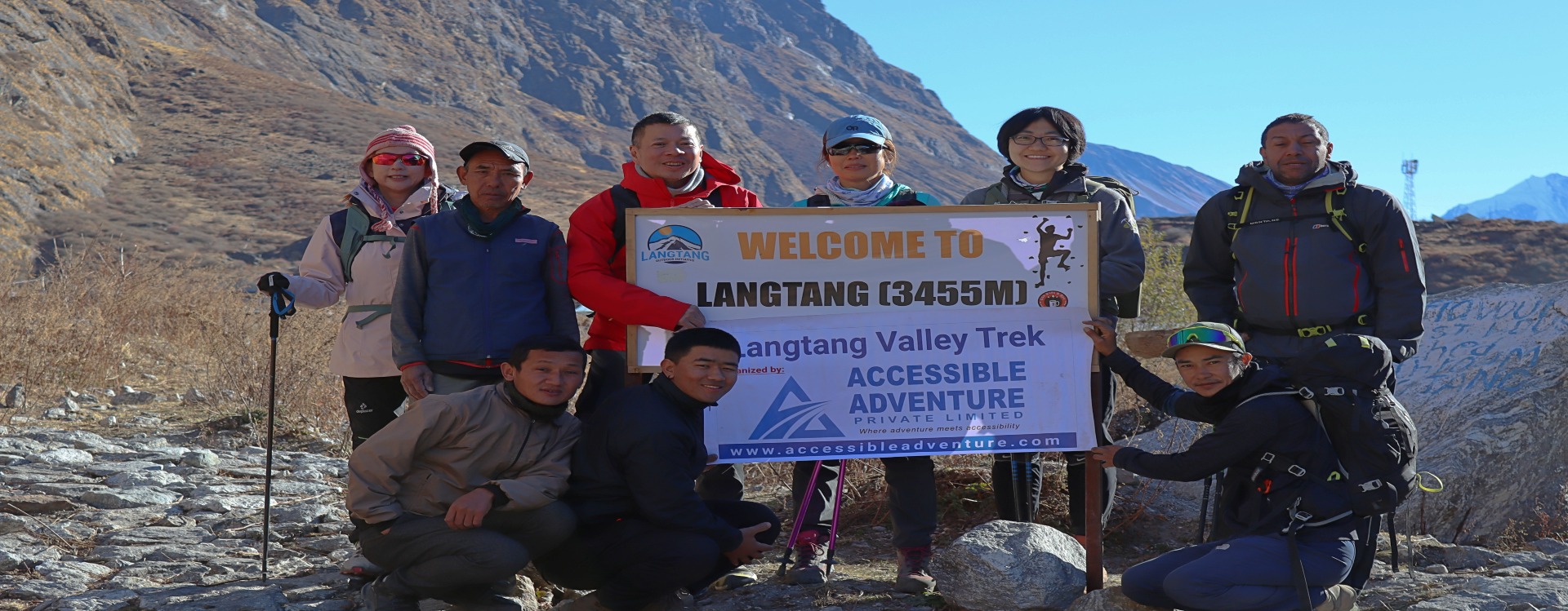 Langtang Valley Trek in Nepal A group of hikers pausing for a photo in front of a sign welcoming them to Langtang Valley at an elevation of 3455 meters.