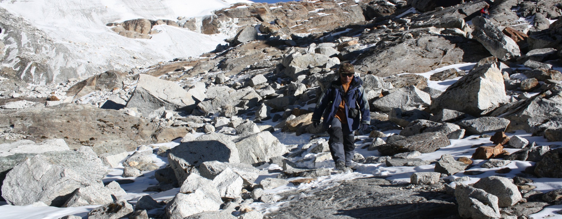This image captures a trekker navigating a rocky, high-altitude terrain in the Himalayas, Mera Peak Summit.