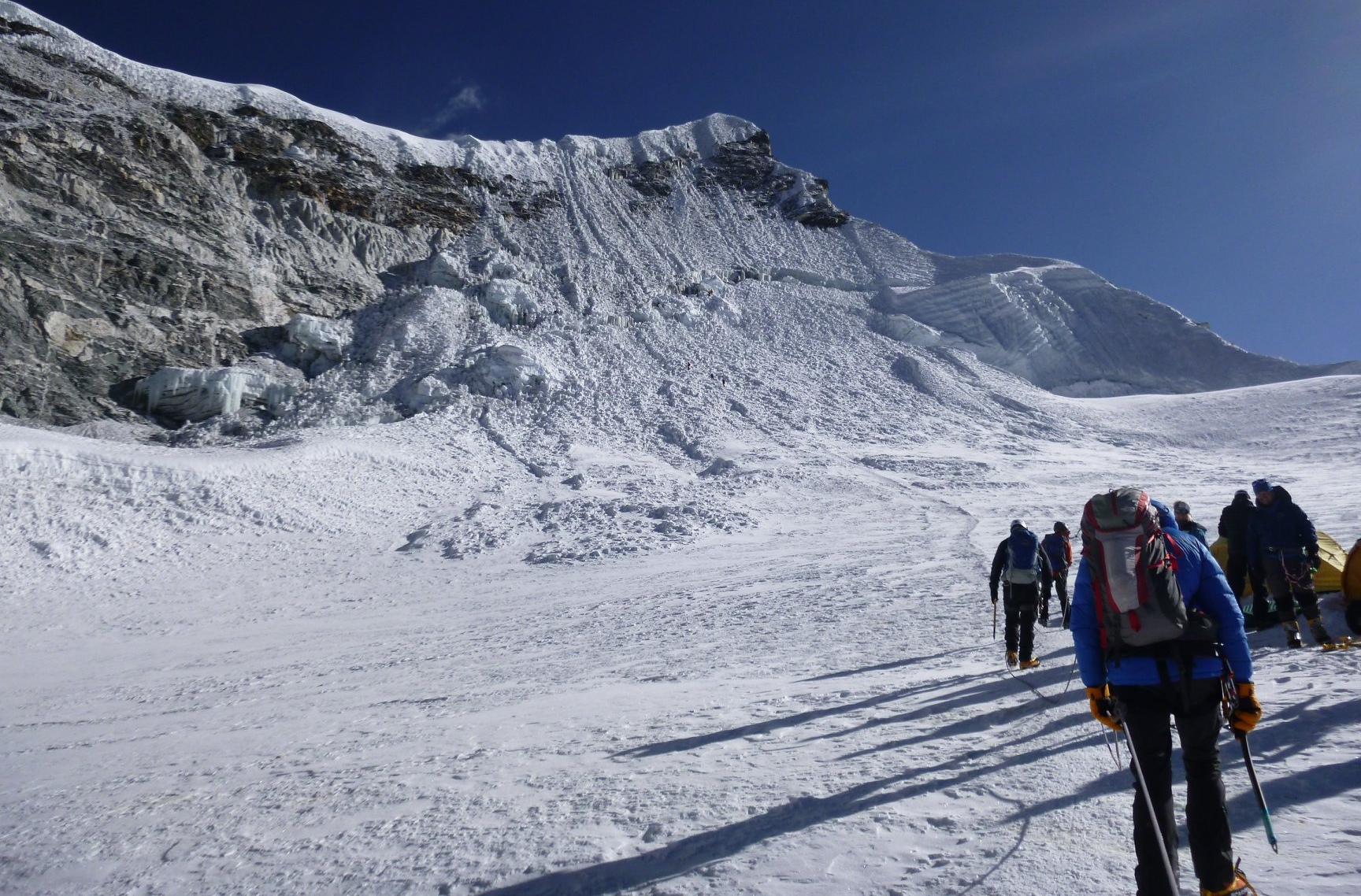 Wide view of Island Peak's headwall showing the full scale of the fixed-rope route and climbers in line