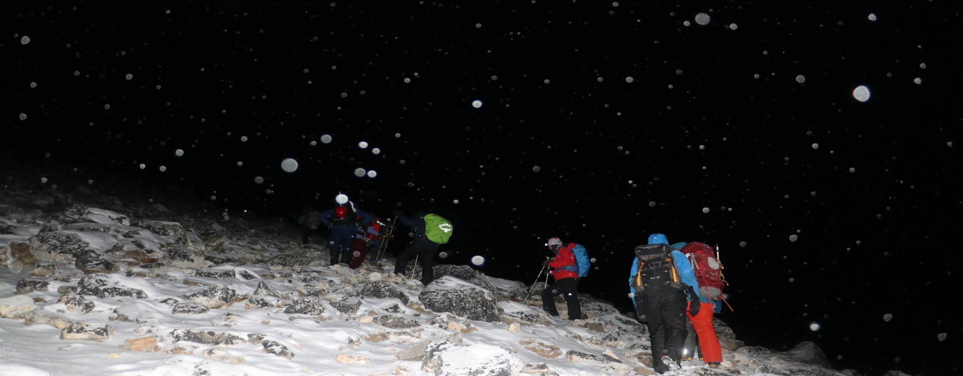 Headlamps ascending rocky trail Climbers ascending Island Peak before dawn with headlamps