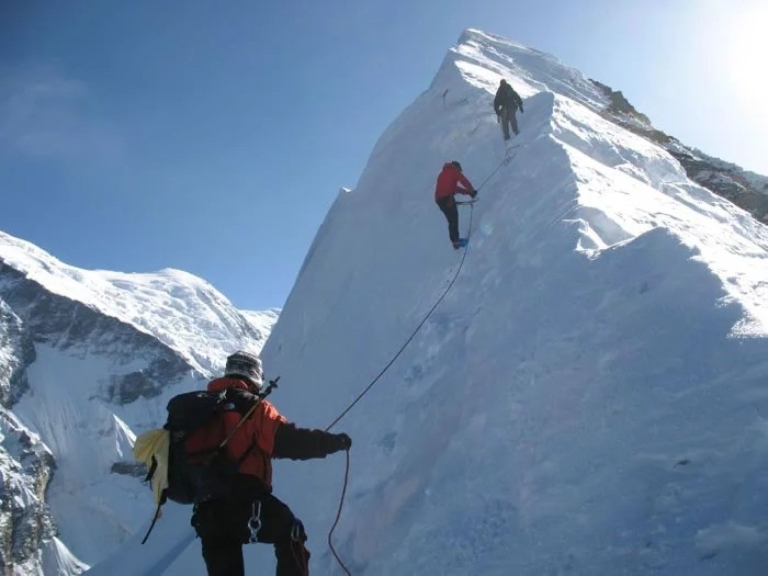 Hiker crossing a suspension bridge in the Khumbu region with a loaded trekking pack