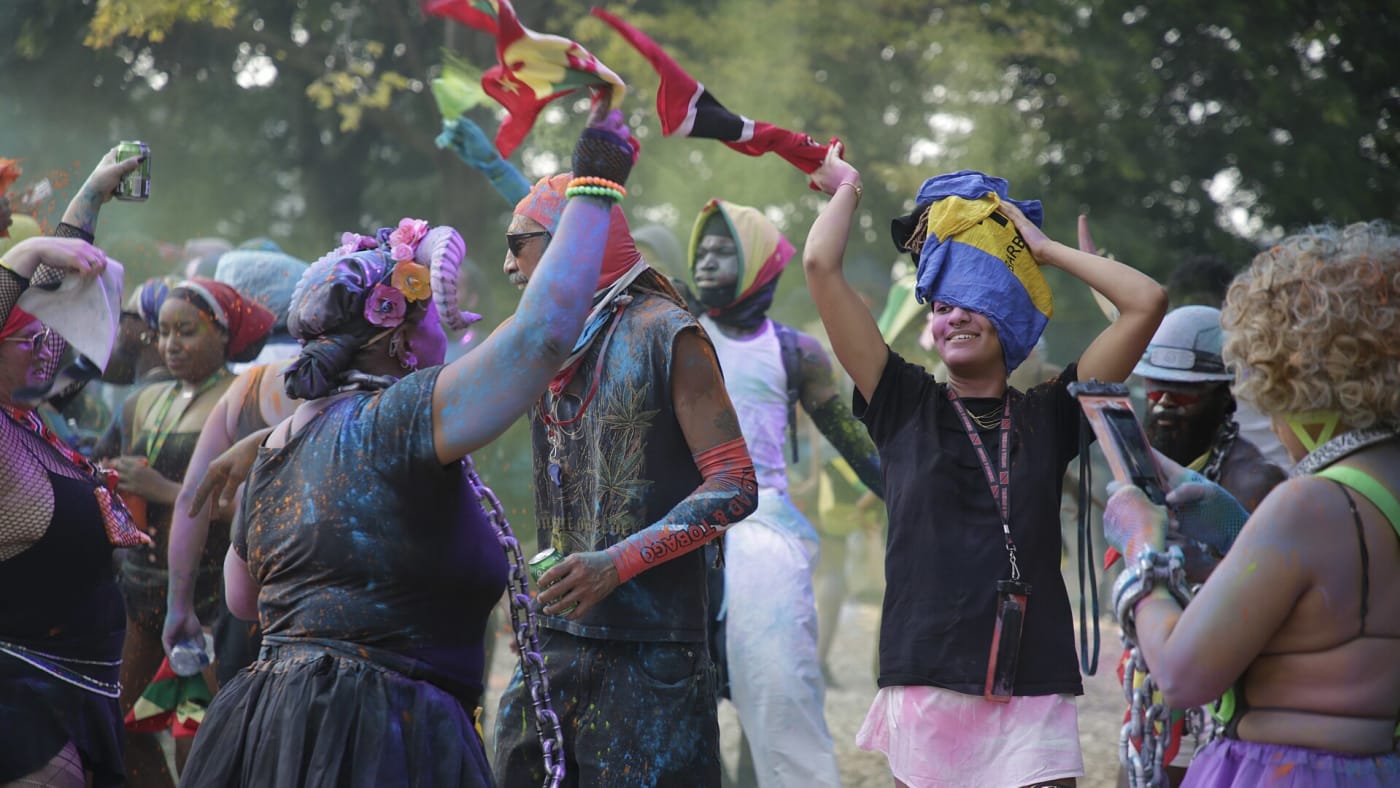 J'ouvert revellers in paint and powder waving flags