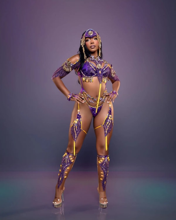 Woman in purple and gold beaded bikini carnival costume with headpiece and leg pieces for One Island Band Minnesota-Vikings section at Miami Carnival 2026