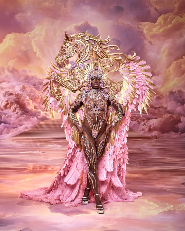 Female performer in Pegasa section of Tribe at Trinidad Carnival 2027 wearing pink and gold feathered wings with horse headpiece
