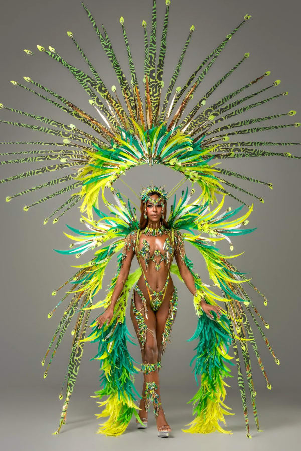 Female carnival dancer in Spirit IVY green and yellow feathered bikini costume with large headdress and wings, Trinidad Carnival 2027