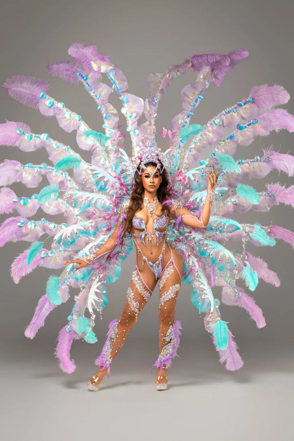 Female carnival dancer in Spirit MIST section costume with large purple teal and pink feathered wings at Trinidad Carnival 2027