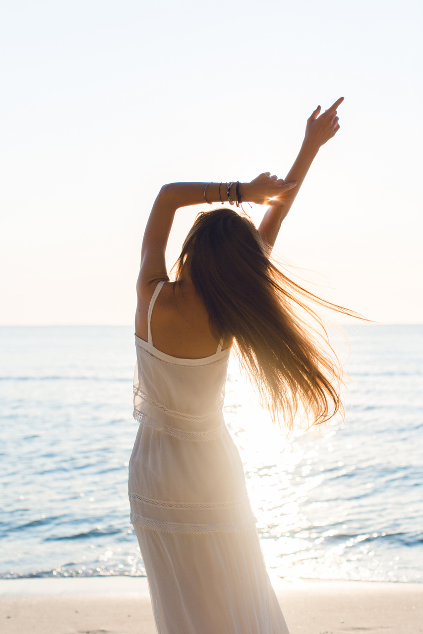 mulher na praia com vestido branco para mostrar as tendências de moda primavera/verão 2021