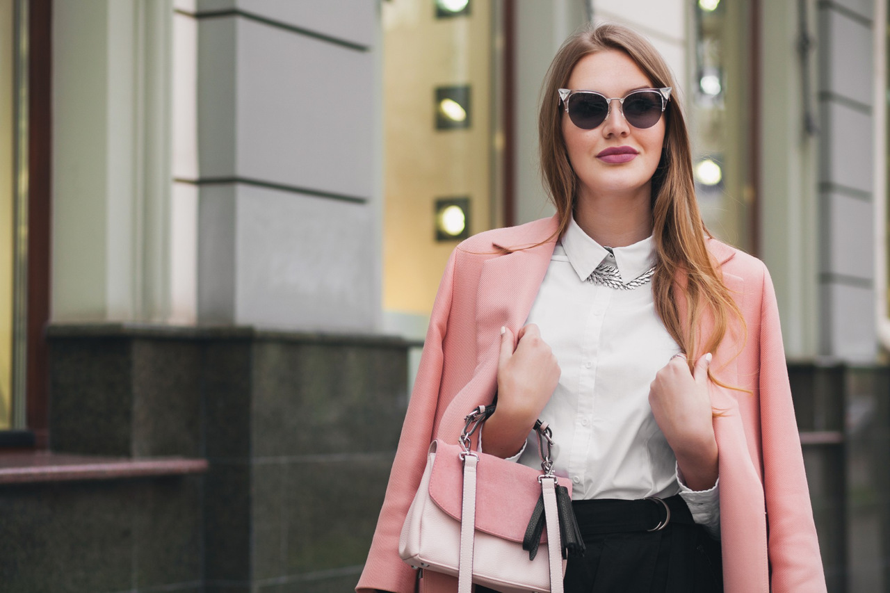 mulher estilosa com óculos de sol, blazer e bolsa para demonstrar como combinar acessórios