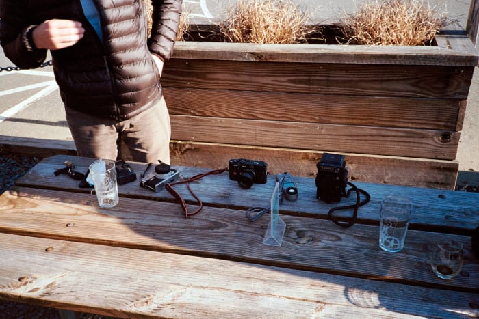 picnic table with various cameras and drinks