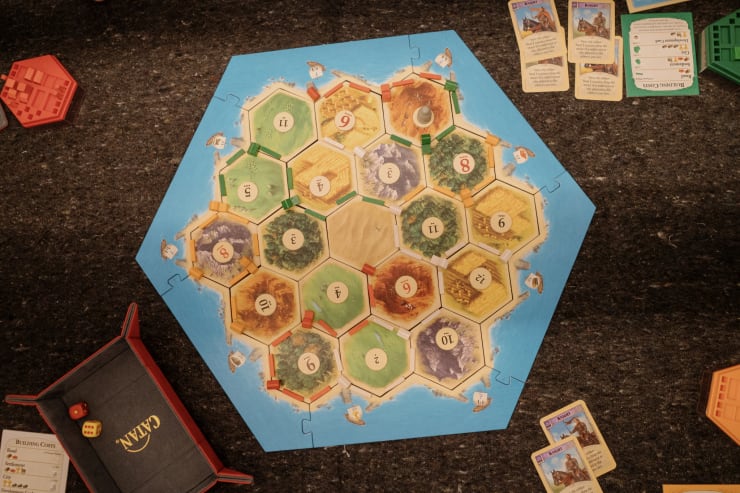 overhead view of a hexagon shaped game board surrounded by game cards and accessories