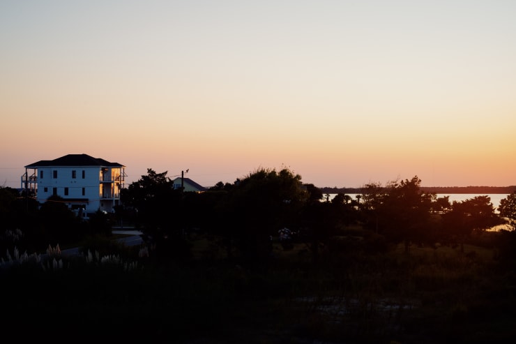 wooded inlet coast during sunset with incomplete beach house in the distance