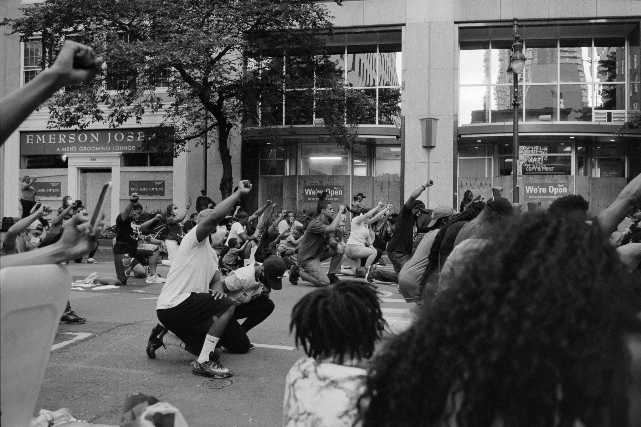 people in the street taking a knee with fists up