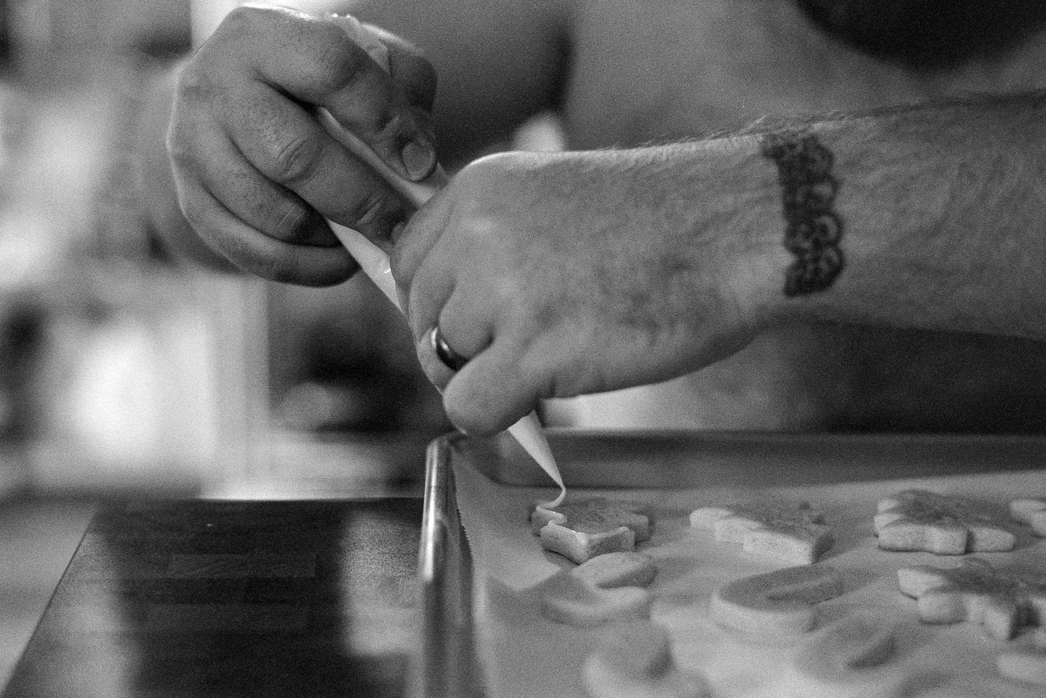 man piping icing onto cookies