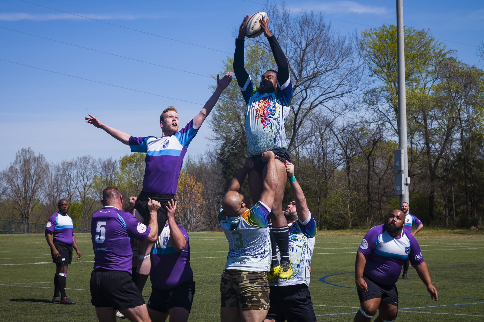 rugby players lifting teammates up to catch ball