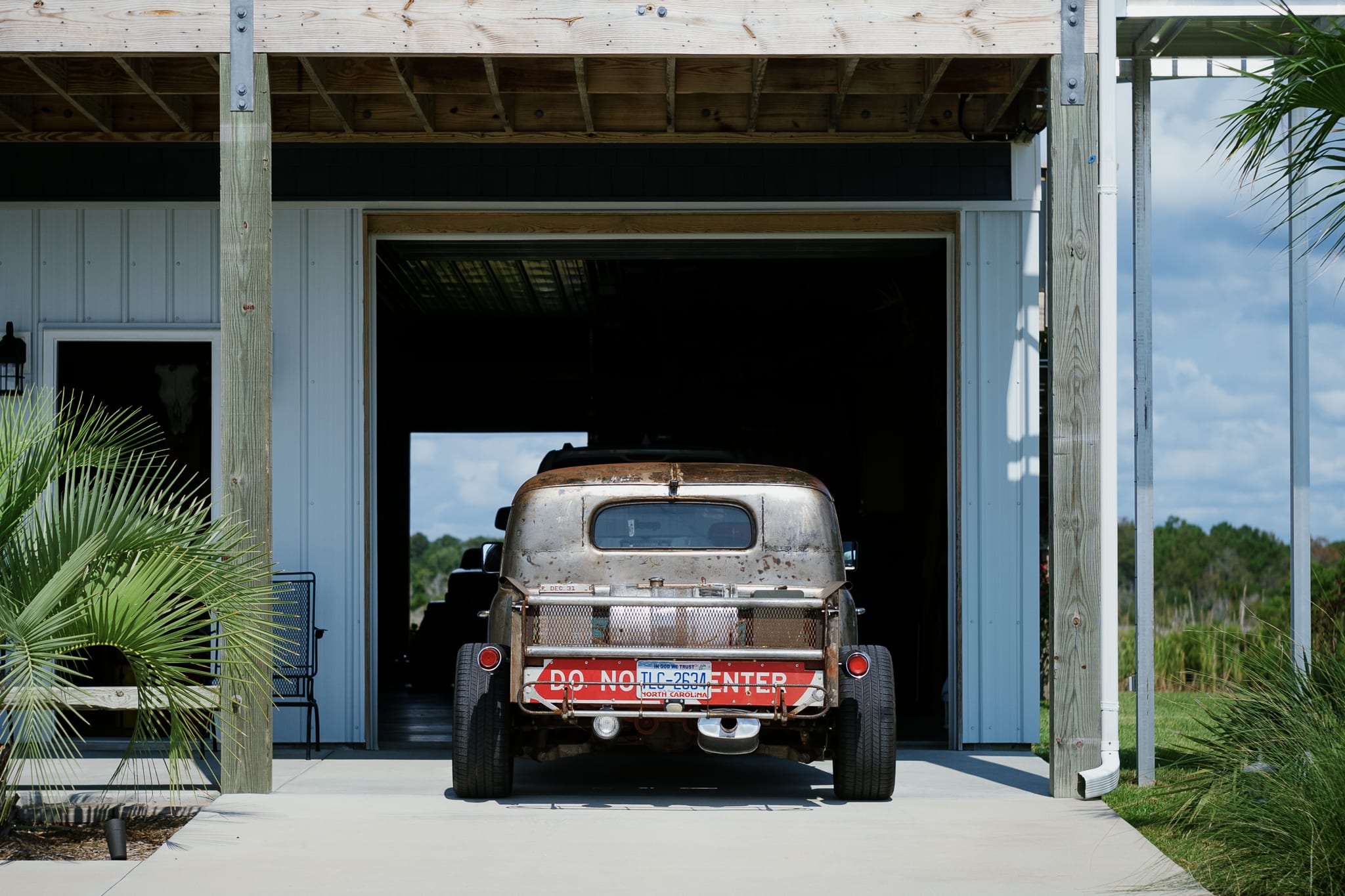 back of a vintage truck parked in front of a garage. tailgate reads 'do not enter'