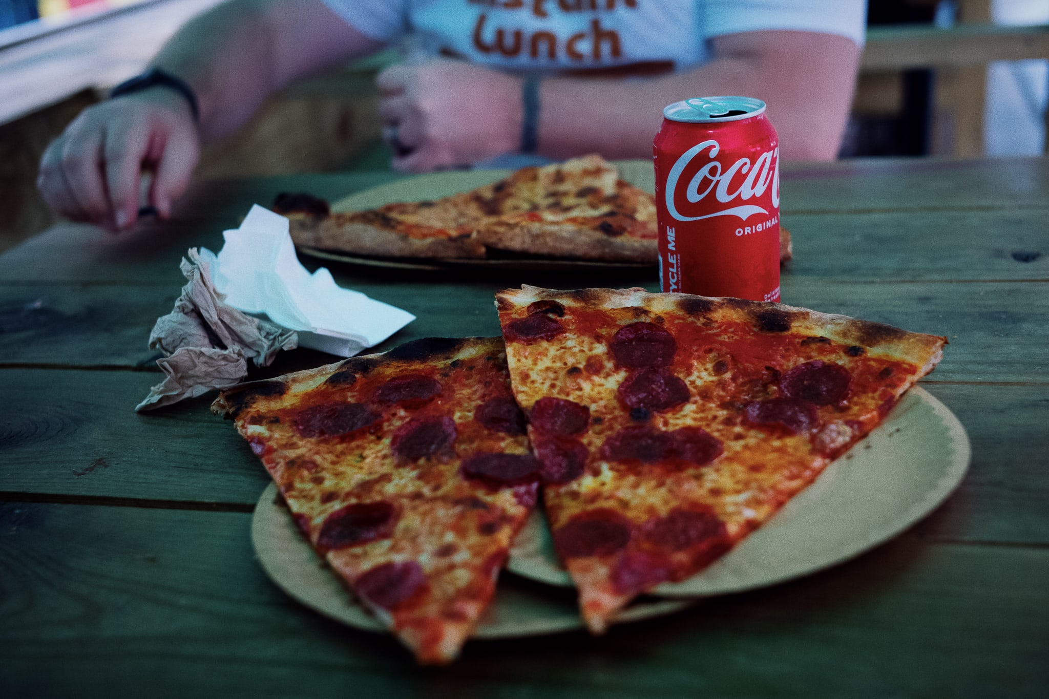 two slices of pepperoni pizza and a coke on a sidewalk table