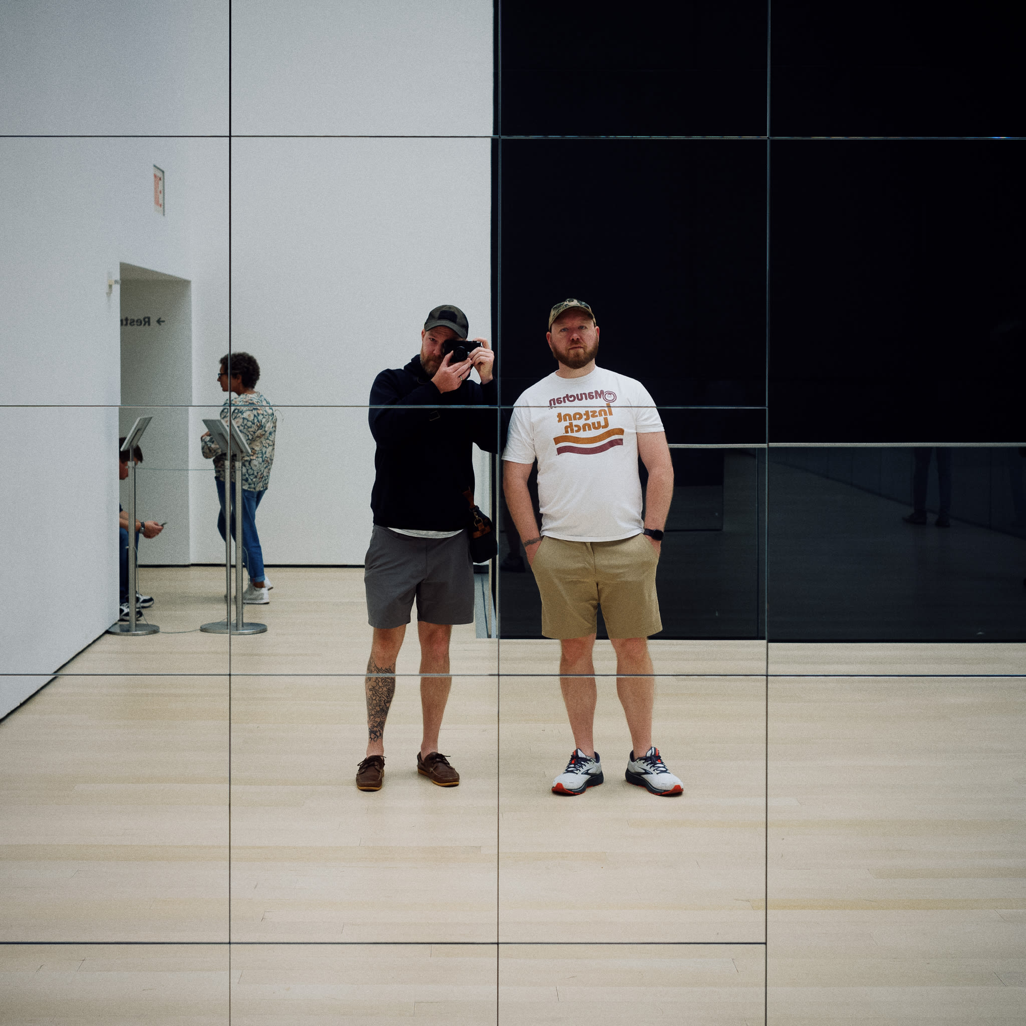 two men reflected in a grid of mirrors installation