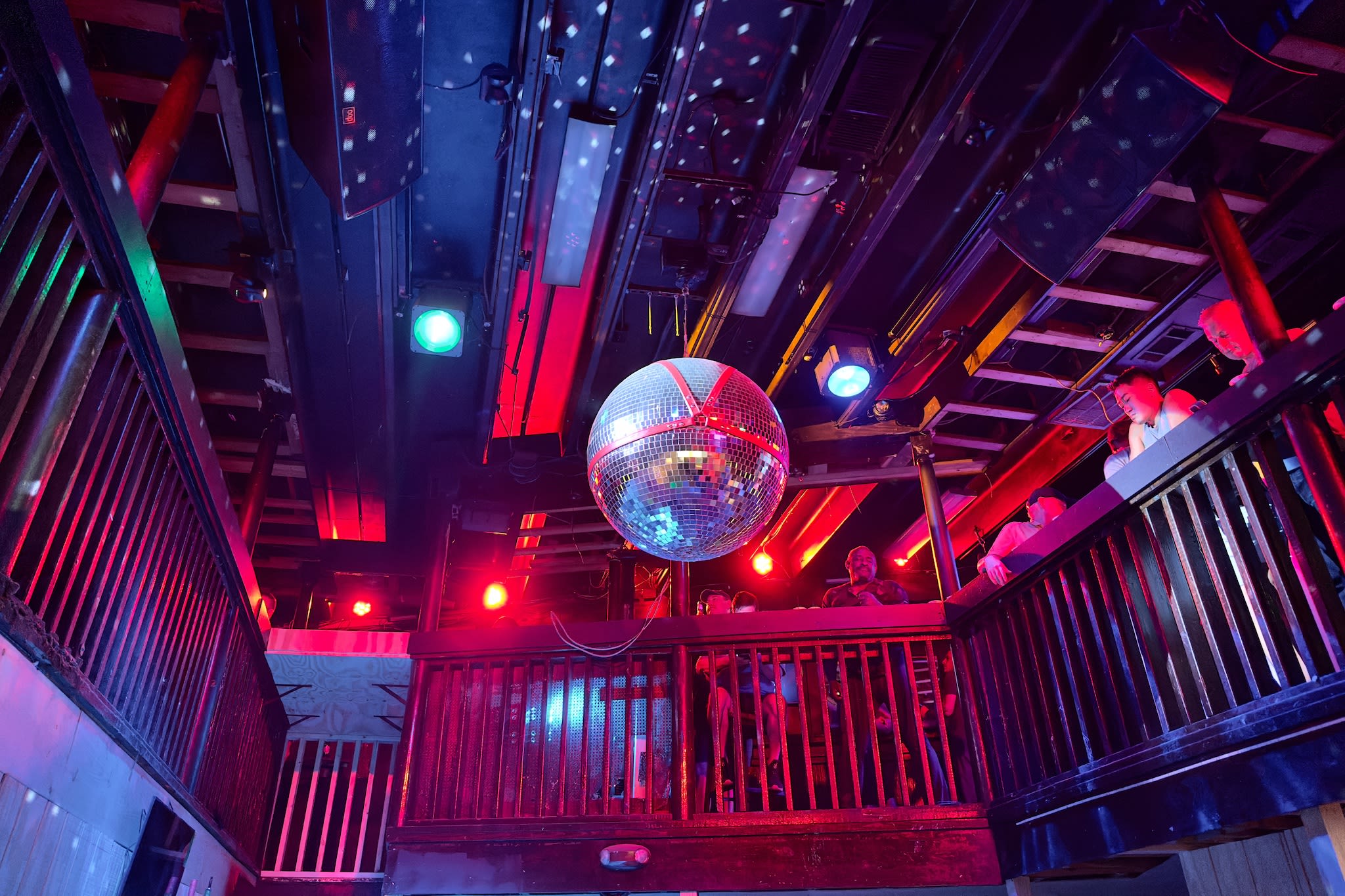 disco ball hanging from the ceiling with an orange leather harness wrapped around it