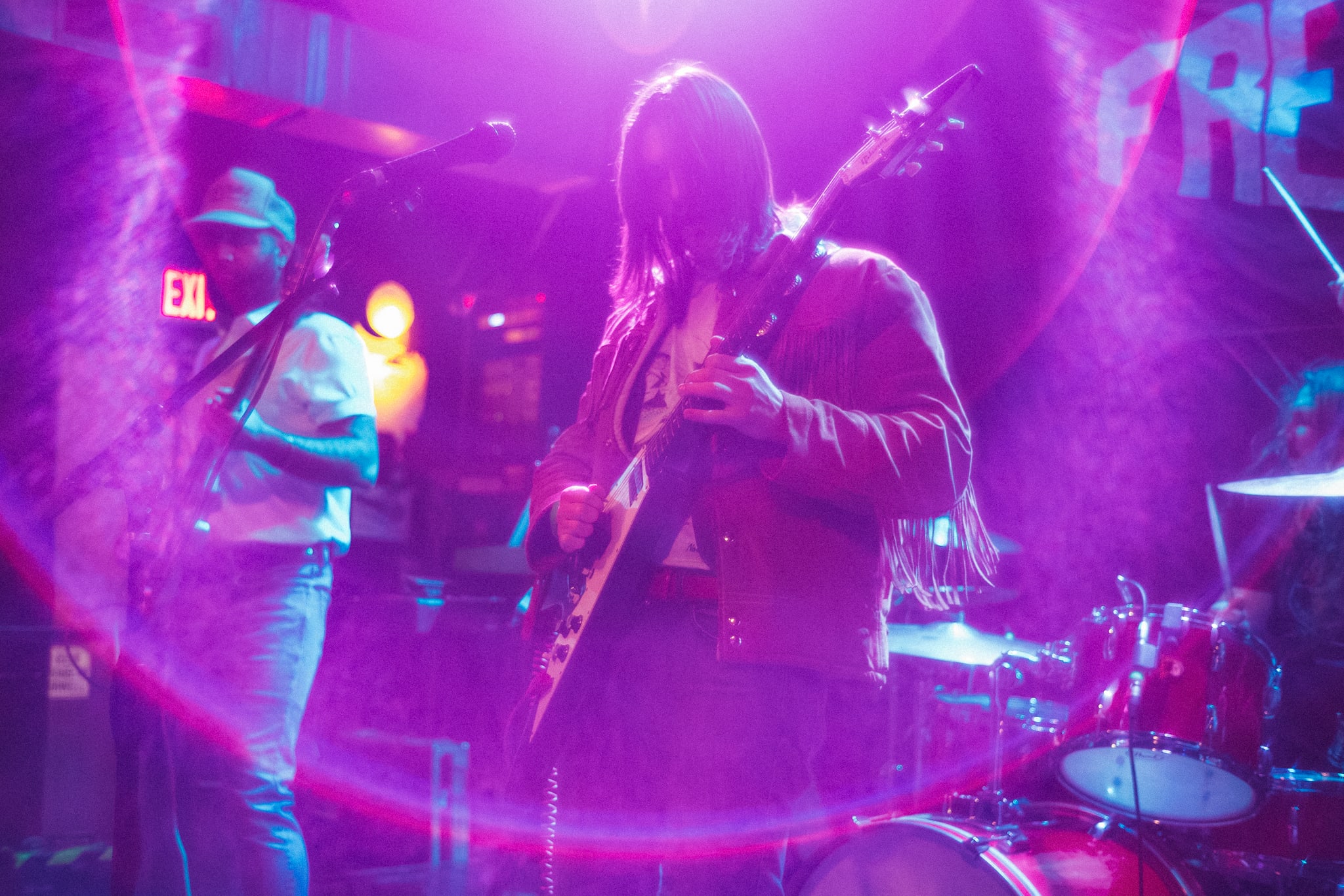 a long-haired man on stage intensely playing a guitar solo, blanketed in stage lighting