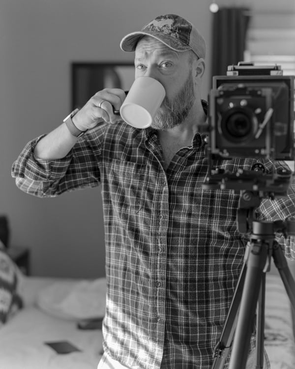 A man takes a self-portrait in front of a mirror with a large format camera