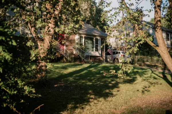 front lawn of a brick house through a pair of trees